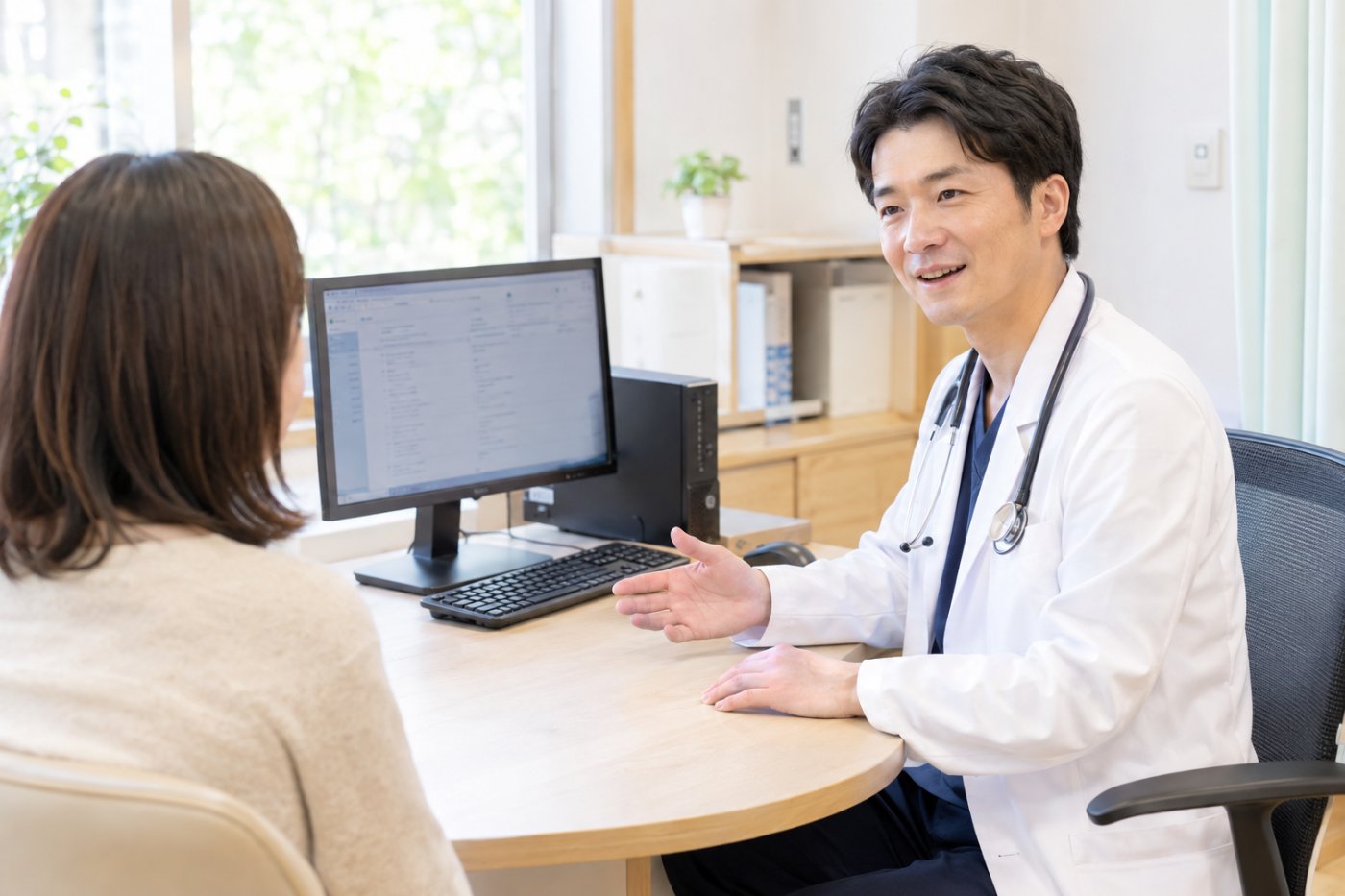 診察室でデスクトップPCの電子カルテを見ながら説明する医師