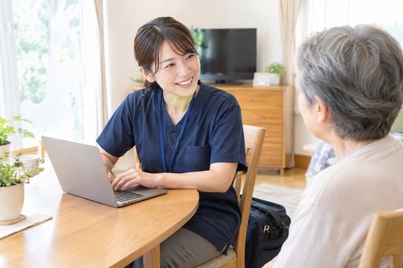 訪問先で軽量ノートPCに記録しながら高齢者と話す訪問看護師