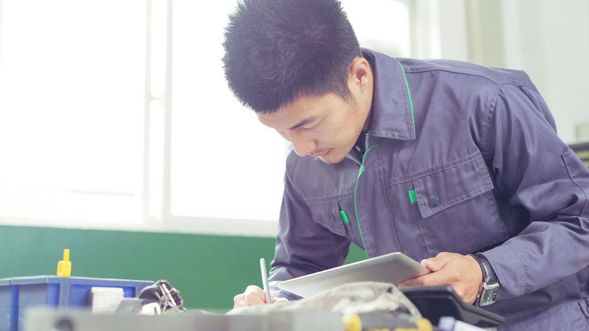工場の事務所でノートPCの動作を一緒に確認する作業着の男性たち